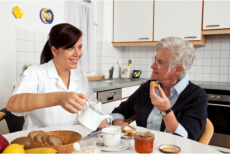 Nurse pouring a cup of milk while listening to an elderly