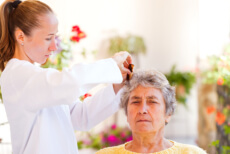 Nurse combing the hair of an elderly
